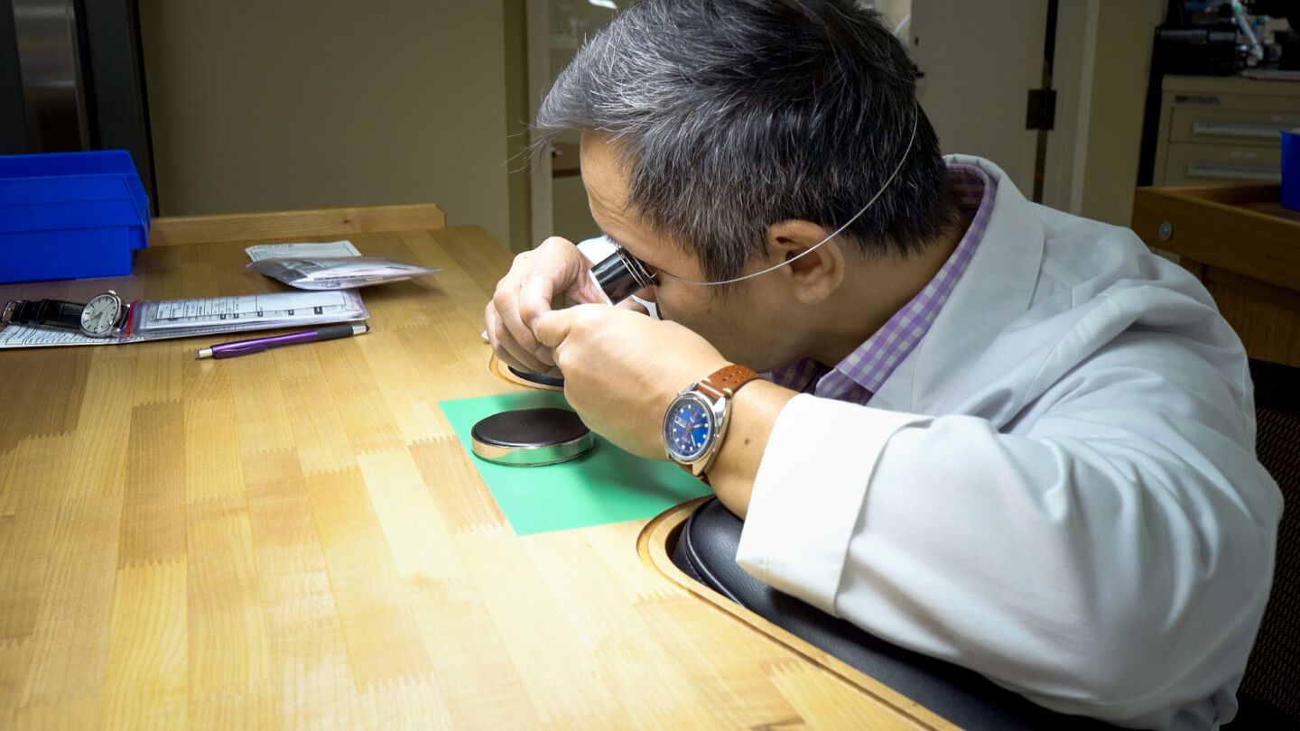 A Ben Bridge watchmaker inspects a watch movement looking through his loupe. 