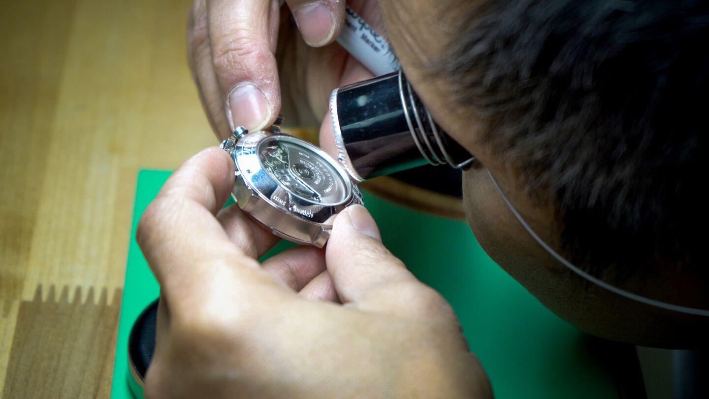 A Ben Bridge watchmaker inspects a luxury watch movement.