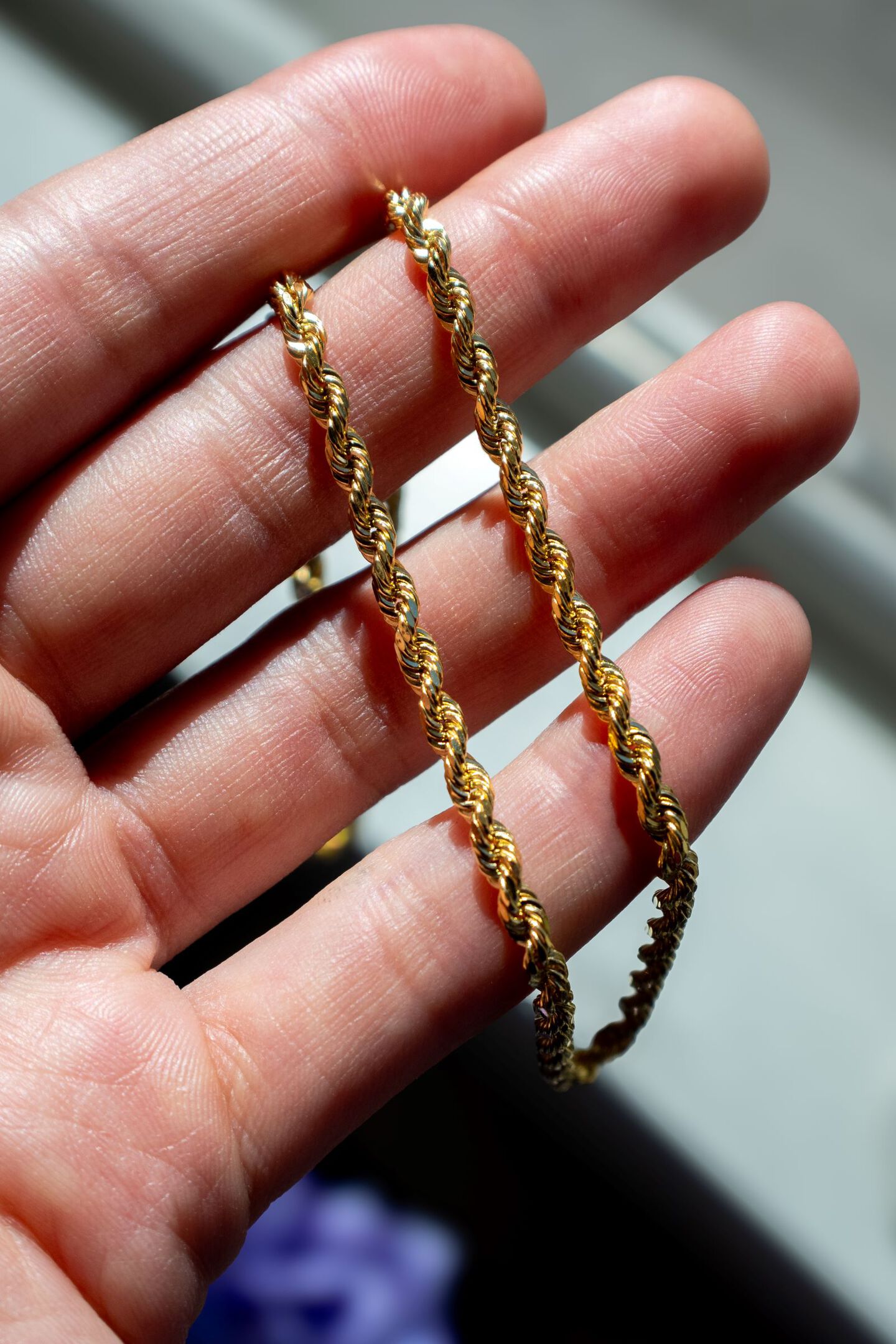 Yellow gold rope chain shines in the palm of someone's hand