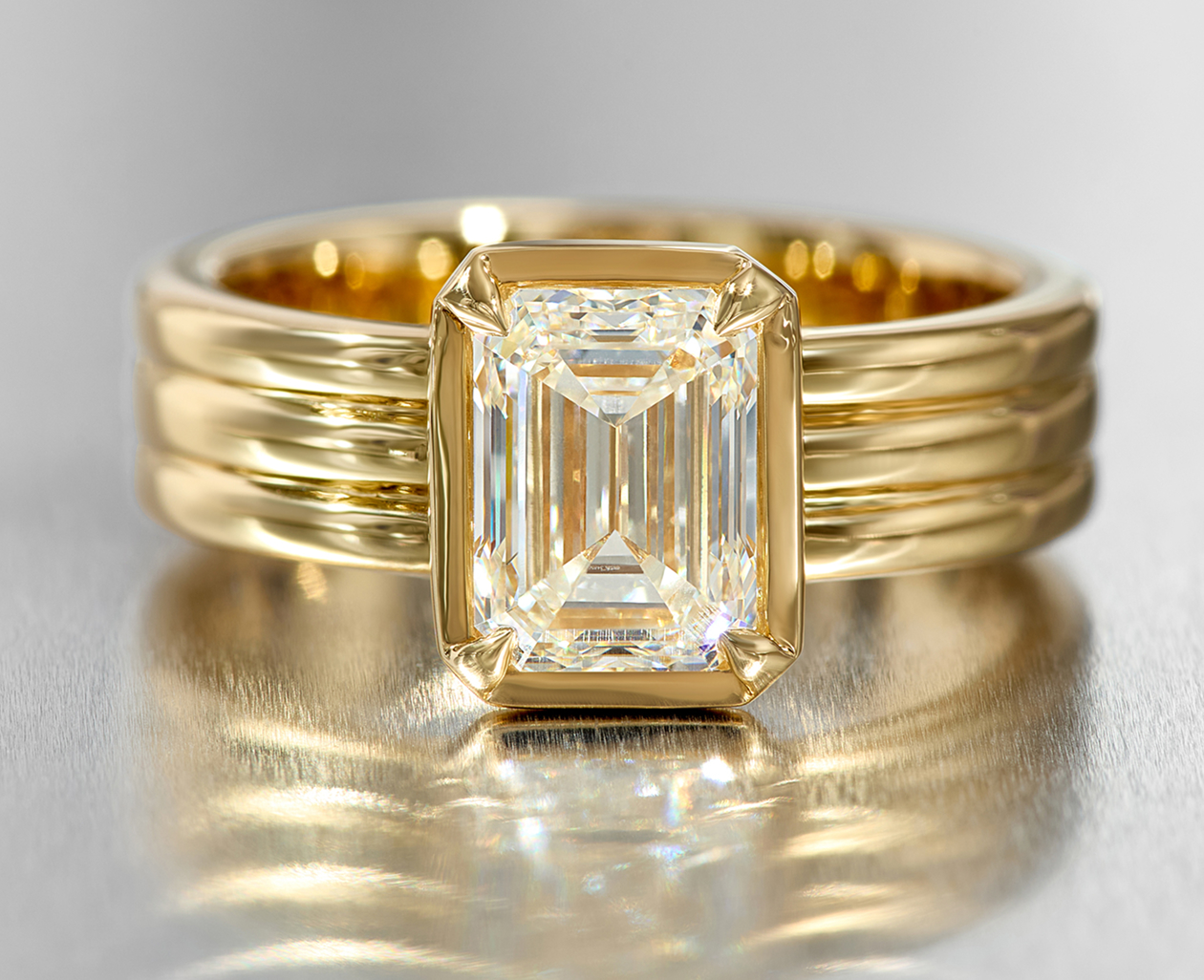 A solitaire diamond engagement ring with a three-row band and bezel
set emerald cut diamond.